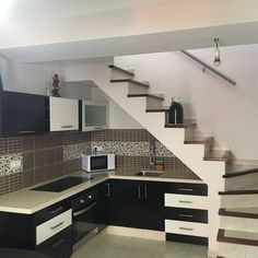 a kitchen with black cabinets and white stairs