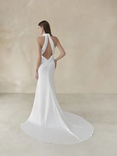 a woman in a white wedding dress with an open back and low neckline is looking down at the floor