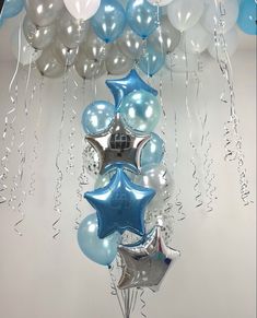 balloons and streamers are hanging from the ceiling in front of a white wall with blue and silver stars