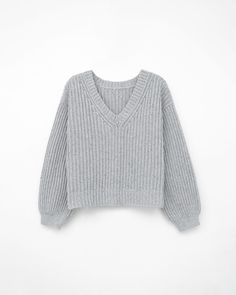 a gray sweater hanging on a white wall, with the top part of it folded up