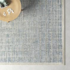 a blue rug on the floor next to a table with a vase and two pictures