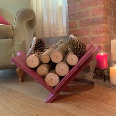 a pile of logs sitting on top of a wooden floor next to a chair and candle