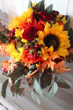 a bridal bouquet with sunflowers, roses and berries