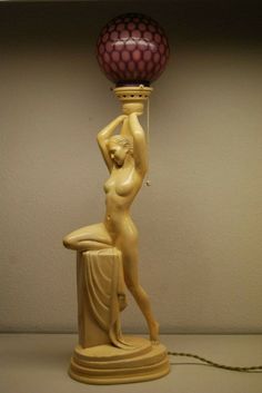 a lamp with a woman holding a ball on it's arm and sitting on a stool