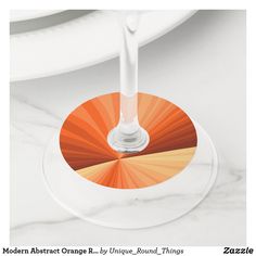 an orange and white drink glass sitting on top of a marble table next to plates