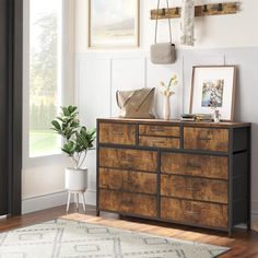 a room with a large wooden dresser and pictures on the wall, along with a potted plant