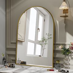 a large mirror sitting on top of a bathroom counter next to a vase with flowers