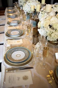 the table is set with white flowers and silverware, candles and napkins on it