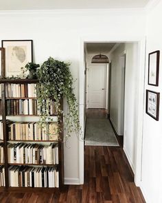 a book shelf filled with lots of books next to a white door and wooden floor