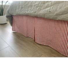 a bed with red and white striped bedspread next to a potted plant