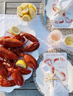 lobsters and lemon slices are on plates next to the menu