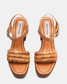 Get ready to step into style with DOMINICA. This platform sandal features a wooden bottom and block heel, providing both comfort and height. The raffia front strap adds a touch of natural charm to any outfit. Take your wardrobe to the next level with this unique and playful sandal. 4 inch heel height 1.5 inch platform Raffia and leather upper material Unlined Synthetic sock Synthetic sole Imported Trendy Natural Straw Sandals, Chic Sandals With Wooden Heel And Straw Material, Straw Heels With Wooden Heel, Natural Sandals With Wooden Heel For Summer, Natural Sandals With Wooden Heel For Spring, Natural Sandals With Wooden Heel, Spring Sandals With Wooden Heel In Natural Color, Summer Sandals With Wooden Heel In Natural Color, Straw Sandals With Heel Strap And Block Heel