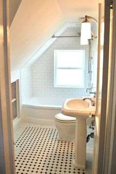 an attic bathroom with black and white floor tiles