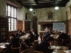 an old school classroom with students sitting at desks and writing on their notebooks