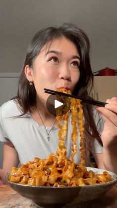 a woman eating noodles with chopsticks in her mouth