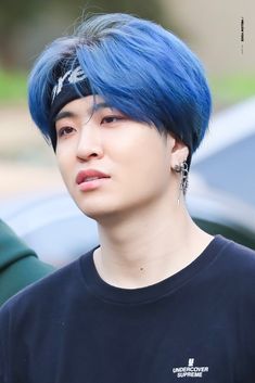 a young man with blue hair wearing a black t - shirt and silver earring