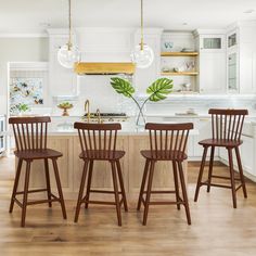 three wooden stools sit in front of a kitchen island