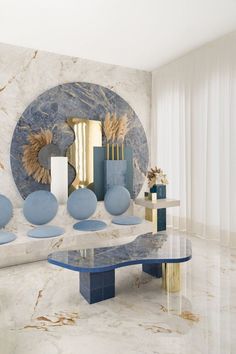 a room with blue and gold decorations on the wall next to a marble table in front of a round mirror