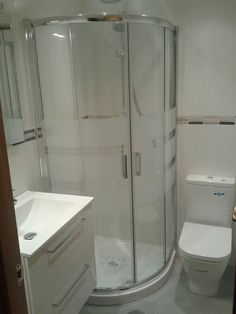 a bathroom with a toilet, sink and shower stall in the middle of the room