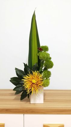 a white vase filled with green and yellow flowers