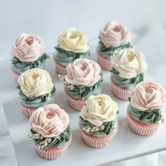 cupcakes decorated with pink and white flowers on a tray