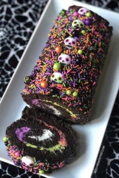 a white plate topped with a chocolate roll covered in sprinkles and skulls