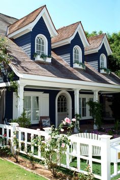 a blue house with white picket fence and flowers