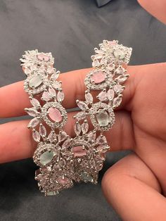 a pair of pink and white earrings in someone's hand