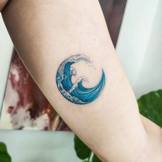 a woman's arm with a blue wave tattoo on it