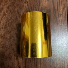 a close up of a gold colored metal object on a wooden table with wood grained surface