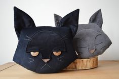 two black and grey cat masks sitting on top of a wooden table