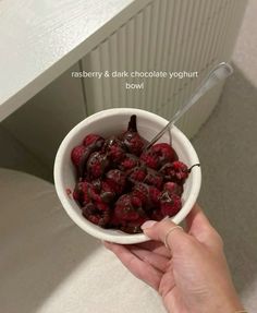 a person holding a bowl of raspberry and chocolate yogurt bowl