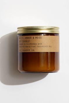 a jar of candle sitting on top of a white wall next to a brown label