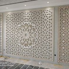 an intricately designed wall in the middle of a room with white walls and flooring