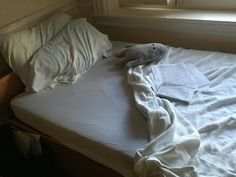 a stuffed animal laying on top of a white bed in a bedroom next to a window