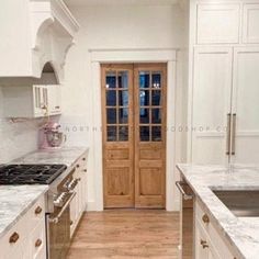 a kitchen with white cabinets and marble counter tops