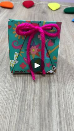 an origami gift box with pink string tied to it