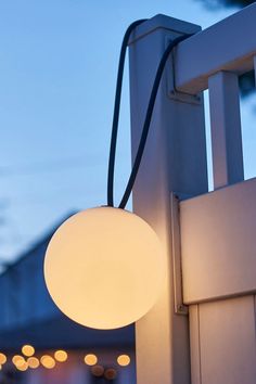 a white light hanging from the side of a wooden fence next to a building at night