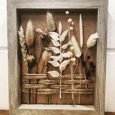 a shadow box with dried flowers in it