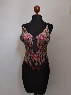 a mannequin wearing a black dress with red, pink and green sequins on it