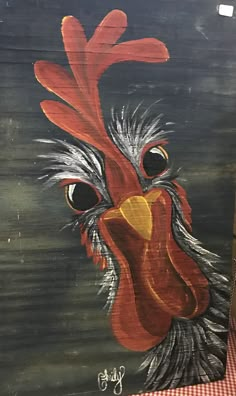 a painting of a rooster on a black board with red and white checkered table cloth