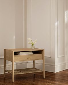 a small wooden table with a vase on top and some books in front of it