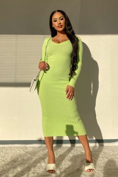 a woman in a lime green dress standing against a wall with her hands on her hips