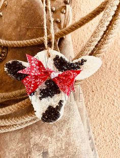 a christmas ornament hanging from a rope on a coat with a red bow