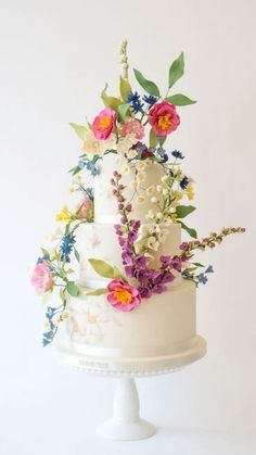 a three tiered white cake with colorful flowers on top