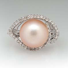 This beautiful ring is centered with one (1), post set, cultured saltwater pearl. The pearl is bordered with forty-five (45), prong set, round single cut diamonds. The ring measures 13.8mm at the top, rises 11.4mm above the finger, tapering to 2.1mm wide and 0.8mm thick at the base of the shank. This ring is currently a size 5. Formal Fine Jewelry Pearl Ring With Prong Setting, Brilliant Cut Pearl Ring, Elegant Pear-shaped Pearl Ring For Formal Occasions, Elegant Formal Pear-shaped Pearl Ring, Diamond Pearl Ring With Pave Setting For Formal Events, Diamond Pearl Ring With Pave Setting For Formal Occasions, Round Diamond Ring With Akoya Pearl And Diamond Accents, Round Akoya Pearl Diamond Ring With Accents, Formal Diamond Pearl Ring With Pave Setting