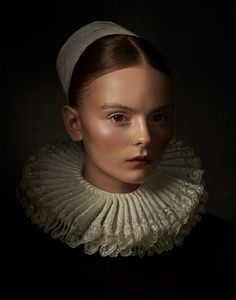 a woman with a white headband and black dress is looking at the camera while wearing a white collar