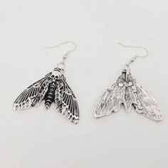 two silver earrings with black and white moths on them