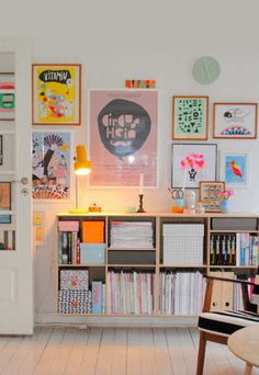 a living room filled with lots of books and pictures on the wall next to a chair