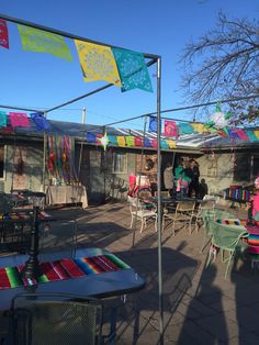 an outdoor patio with tables and chairs covered in colorful flags